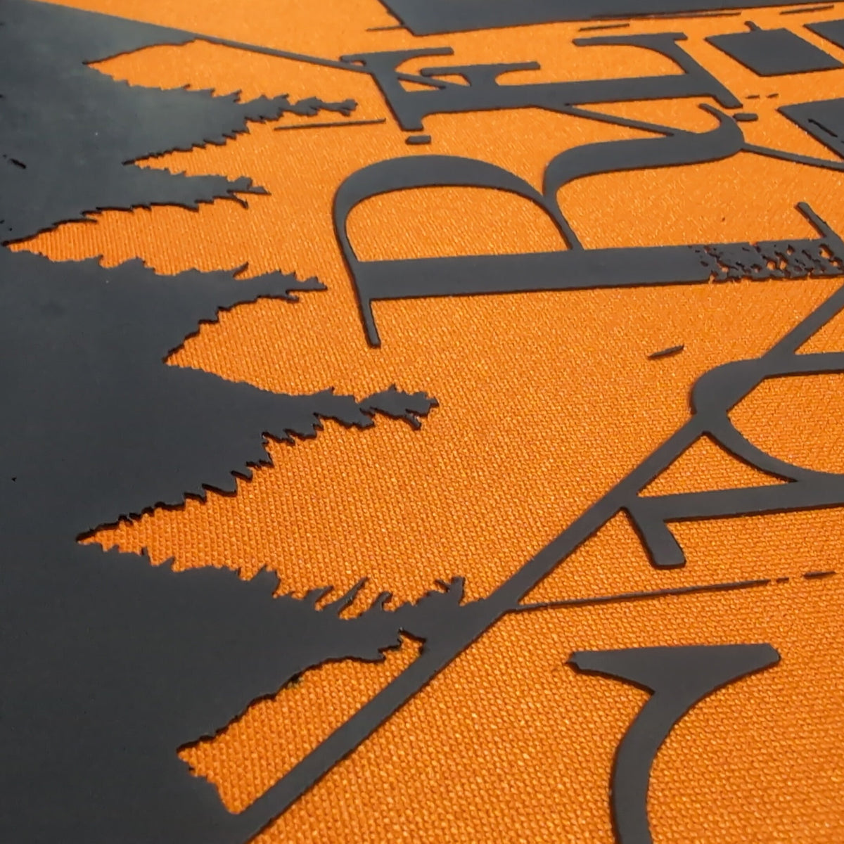 Close-up of a textured orange surface with a large black abstract graphic and stylized lettering.