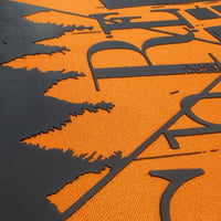 Close-up of a textured orange surface with a large black abstract graphic and stylized lettering.